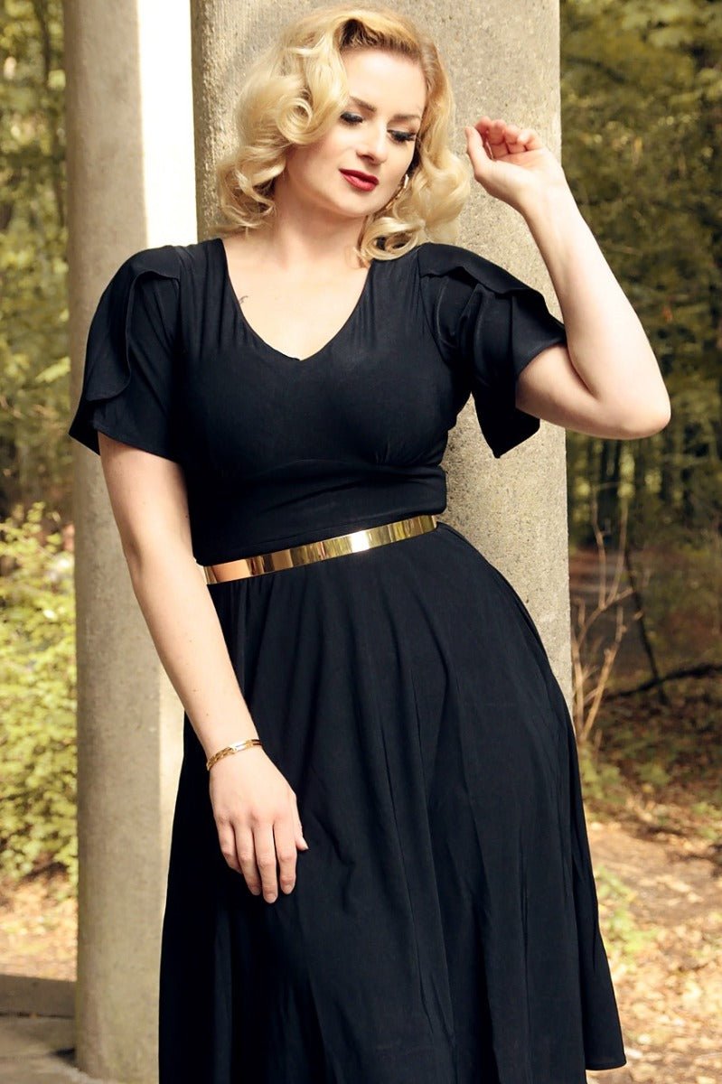 woman wears our Janice petal sleeve swing dress, in black, in countryside