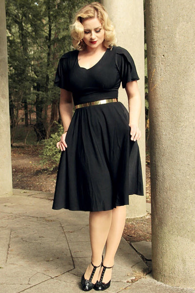 woman wears our Janice petal sleeve swing dress, in black, in countryside