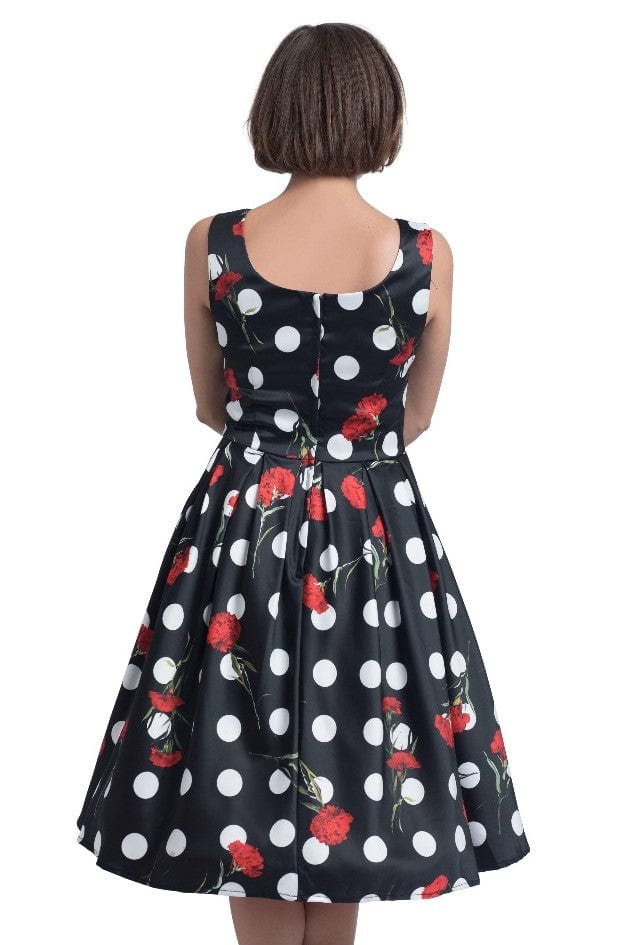 Model wearing black scoop neckline dress in large white spots and red roses print back view