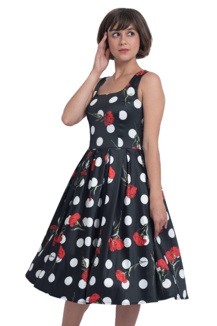 Model wearing black scoop neckline dress in large white spots and red roses print