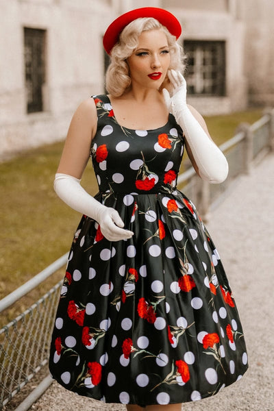 Model wearing black scoop neckline dress in large white spots and red roses print